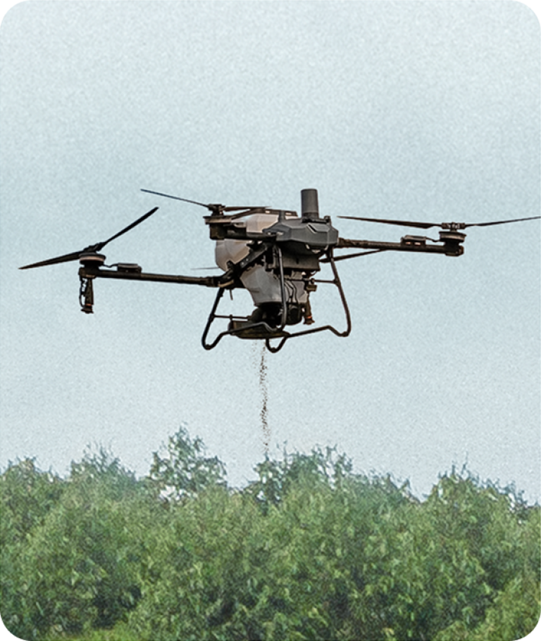 Drone spraying pesticide over a green crop field under a gray sky